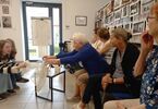 Zdjęcie: Seniorzy siedzą pod regałem z książkami