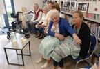 Zdjęcie: Seniorzy siedzą pod regałem z książkami
