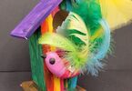 Zdjęcie: Ptaszek handmade z kolorowymi piórami wystający z drewnianego, kolorowego domku