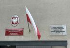 Zdjęcie: ściana budynku z godłem i flagą polski, czerwoną tablicą dzielnicowego biura finansów oświaty targówka i szklaną tabliczką upamiętniającą szkołę nr 114