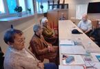 Zdjęcie: Seniorki i seniorzy siedzą za stołem