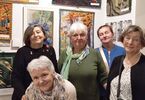 Zdjęcie: grupa pań stojąca na tle wystawy gobelinów