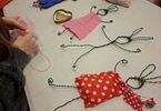 Zdjęcie: warsztaty tworzenia zajączków z drutu, w kolorowych ubrankach: czerwonym w grochy i jasnoróżowym