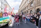 Zdjęcie: kobiety w kolorowych strojach i wiankach na głowie z kwiatów na jezdni, obok chłopiec z chorągiewkami i ludzie obserwujący kolorowy pochór