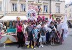 Zdjęcie: grupa osób, kobiety i dzieci przed instalacją artystyczną w kształcie syrenki, z kwiatów, w tle budynek z jasną elewacją