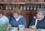 Trzy kobiety siedzące przy stole, w tle słoje z ziołami