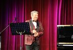 Starszy mężczyzna w czerwonej marynarce trzymający mikrofon