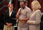 Mężczyzna trzymający dyplom i dwie seniorki
