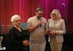 Mężczyzna trzymający mikrofon i dwie seniorki