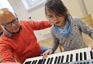 Mężczyzna uczy dziewczynkę gry na keyboardzie