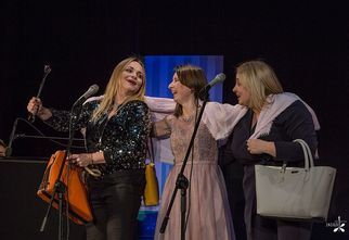 Trzy kobiety stoją na scenie i śmieją się