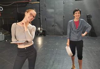 Dwie kobiety stoją na scenie teatralnej