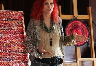 Dorota Koch stoi obok tkaniny zrobionej na szydełku.