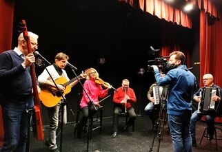 Kapela z Targówka na scenie DK Zacisze nagrywana przez kamerzystę.