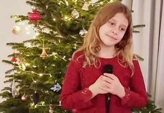 Lena Brzezińska z mikrofonem na tle choinki świątecznie ozdobionej