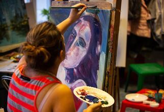 Kobieta maluje obraz na sztaludze