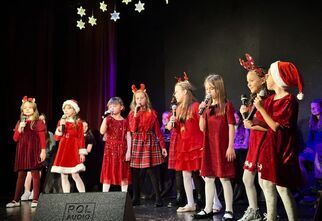 Dziewczynki w czerwonych strojach śpiewają na scenie