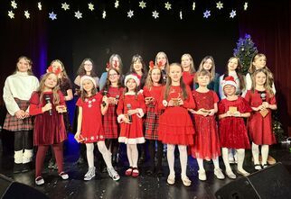 Dziewczynki ubrane świątecznie stoją na scenie