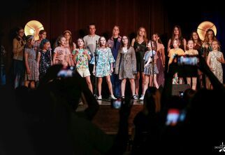 Zdjęcie: dzieci i młodzież na scenie w kolorowych strojach