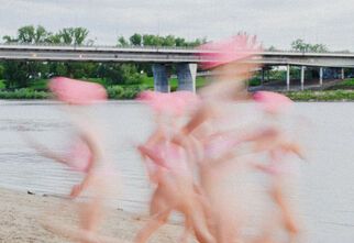 Zdjęcie: postacie rozmyte wędrujące po piasku, w tle rzeka