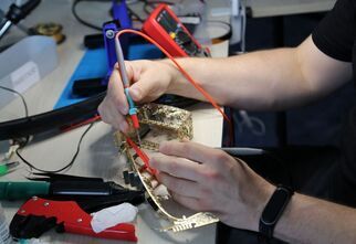 Zdjęcie: męskie ręce podczas lutowania małego sprzętu AGD