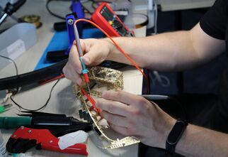 Zdjęcie: męskie ręce podczas lutowania małego sprzętu AGD