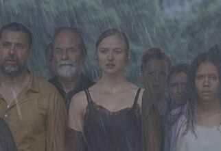 Kadr z filmu Armand, grupa ludzi, kobiety i mężczyźni ze smutnymi minami stojący w strugach deszczu, żródło: filmweb