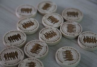 Zdjęcie: pamiątkowe drewniaczki dla uczestników gry terenowej z napisem Małe Historie Wielkich Kobiet i geocaching