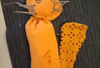 Zdjęcie:  żółty kotek z materiału na szarej tkaninie