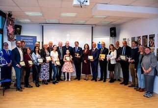 Zdjęcie grupowe: kobiety, mężczyźni, młodzież z tabliczkami grawerowanymi i aniołami