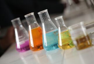 Zdjęcie: Szklane naczynia z kolorowymi cieczami na jasnym blacie