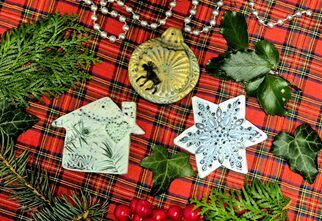 Zdjęcie: trzy gliniane zawieszki, gwiazdka, domek, bombka na kraciastym obrusie