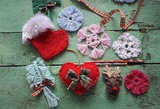 Zdjęcie: na drewnianym podłożu kolorowe ozdoby ręcznie uszyte, gwizdki, serce, rudolf, but mikołaja