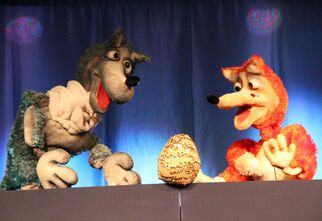 Zdjęcie: Lalki kura i wilk na tle niebieskiej kotary, w środku złote jajko