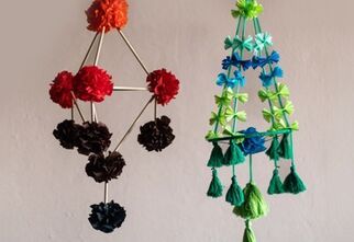 Zdjęcie: dwa kolorowe ludowe etno pająki, ręcznie wykonane, pierwszy po lewej składający się z ośmiu kwiatów i drewnianych patyczków, drugi obok w kolorach turkusowych, błękitnych i zielonych