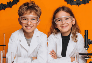 Zdjęcie: chłopiec i dziewczynka w białych fartuchach na pomarańczowym tle z dwoma nietoperzami