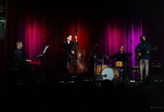 Zdjęcie: grup[a muzyków na scenie z instrumentami na ciemnofioletowym tle