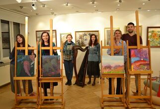 Zdjęcie: grupa czterech młodych osób stojących przy sztalugach z obrazami, z tyłu dwie kobiety przy harfie, w tle obrazy na ścianie