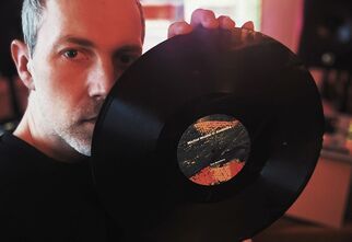 Zdjęcie: Mężczyzna w średnim wieku, trzymający płytę winylową