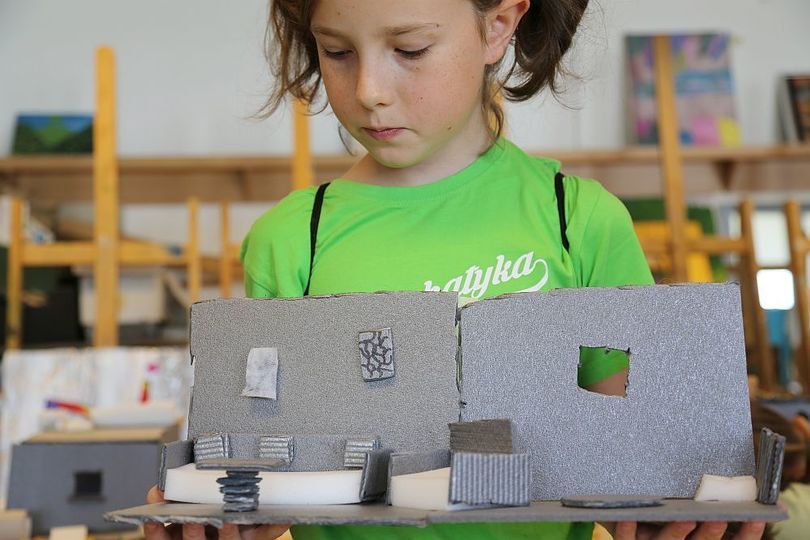 Dziewczynka pokazuje wykonany przez siebie model pokoju