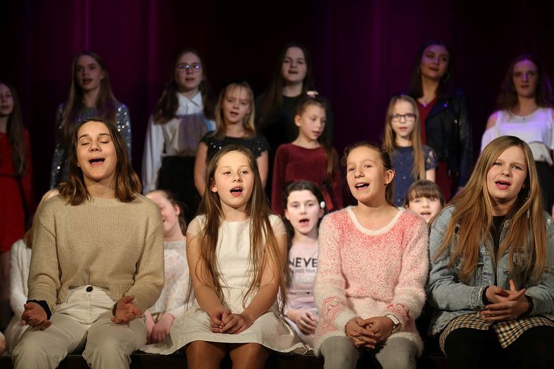 Grupa dziewczyn śpiewa piosenkę na scenie