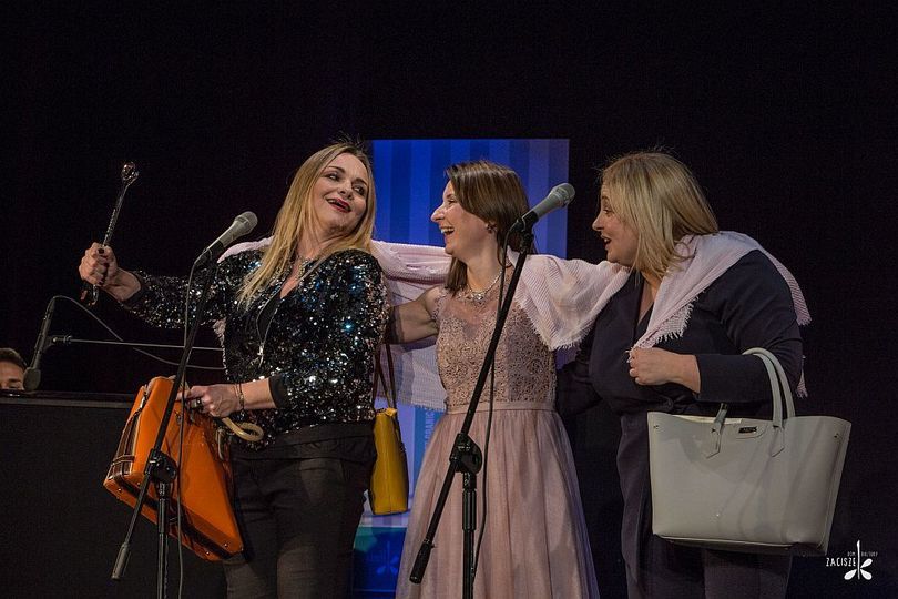 Trzy kobiety stoją na scenie i śmieją się