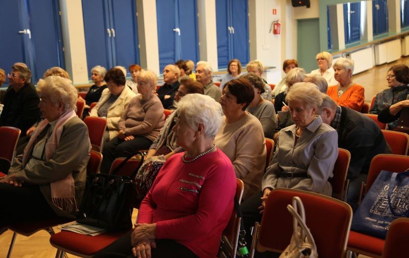 Grupa seniorów słucha na siedząco wykładu
