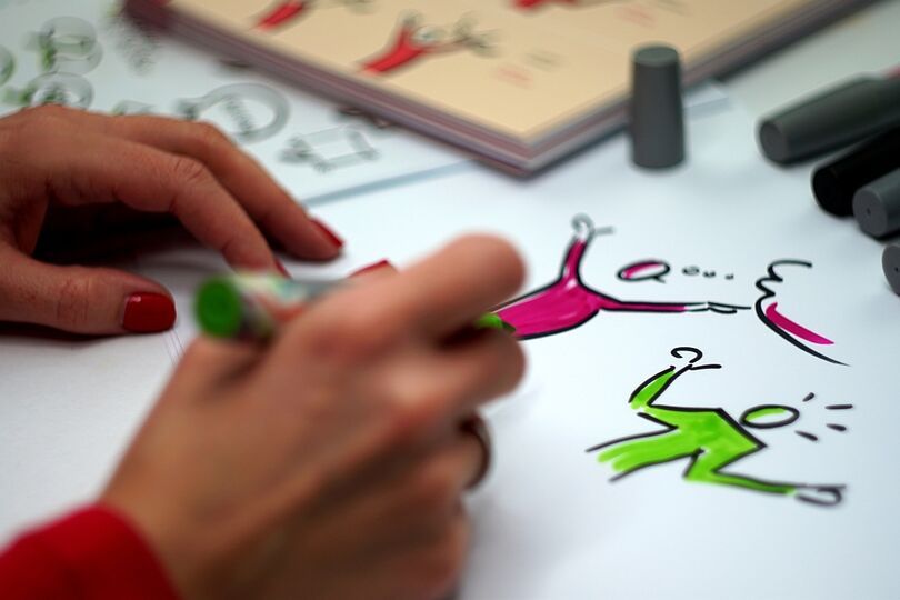 Zdjęcie dłoni z flamastrem podczas pisania notatek za pomocą sketchnotingu.
