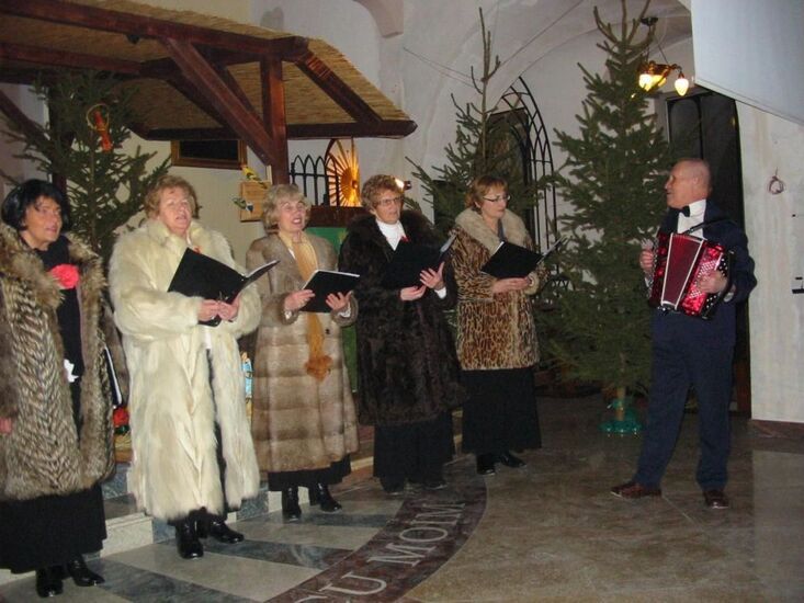 Seniorzy ciepło ubrani śpiewają w kościele.