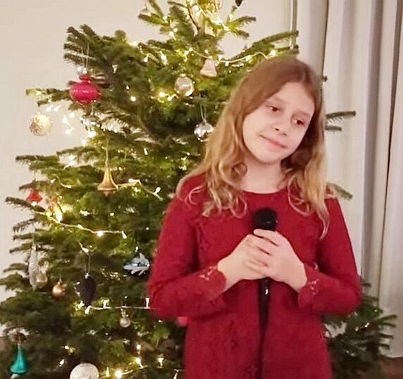 Lena Brzezińska z mikrofonem na tle choinki świątecznie ozdobionej