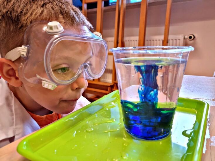 Dziecko przyglądające się wodzie z barwnikiem w plastikowym kubku