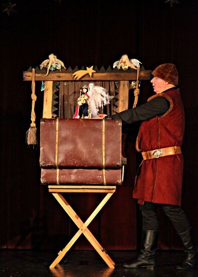 Aktor podczas przedstawienia przy walizce z kukiełkami
