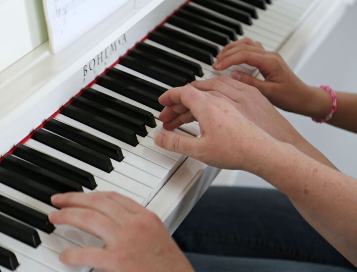 Ręce kobiety i dziecięce na klawiaturze pianina