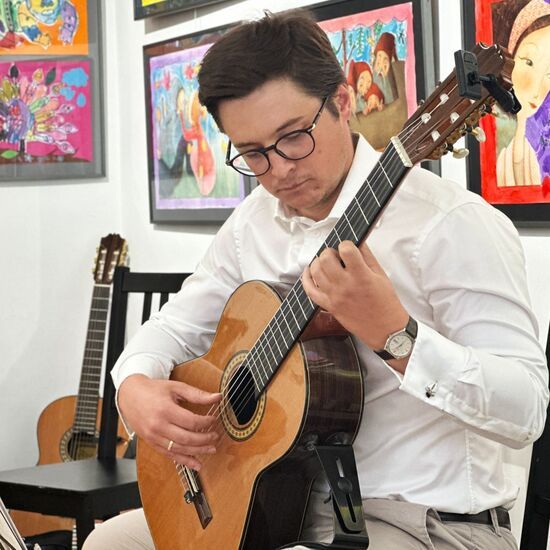 Młody mężczyzna w okularach grający na gitarze